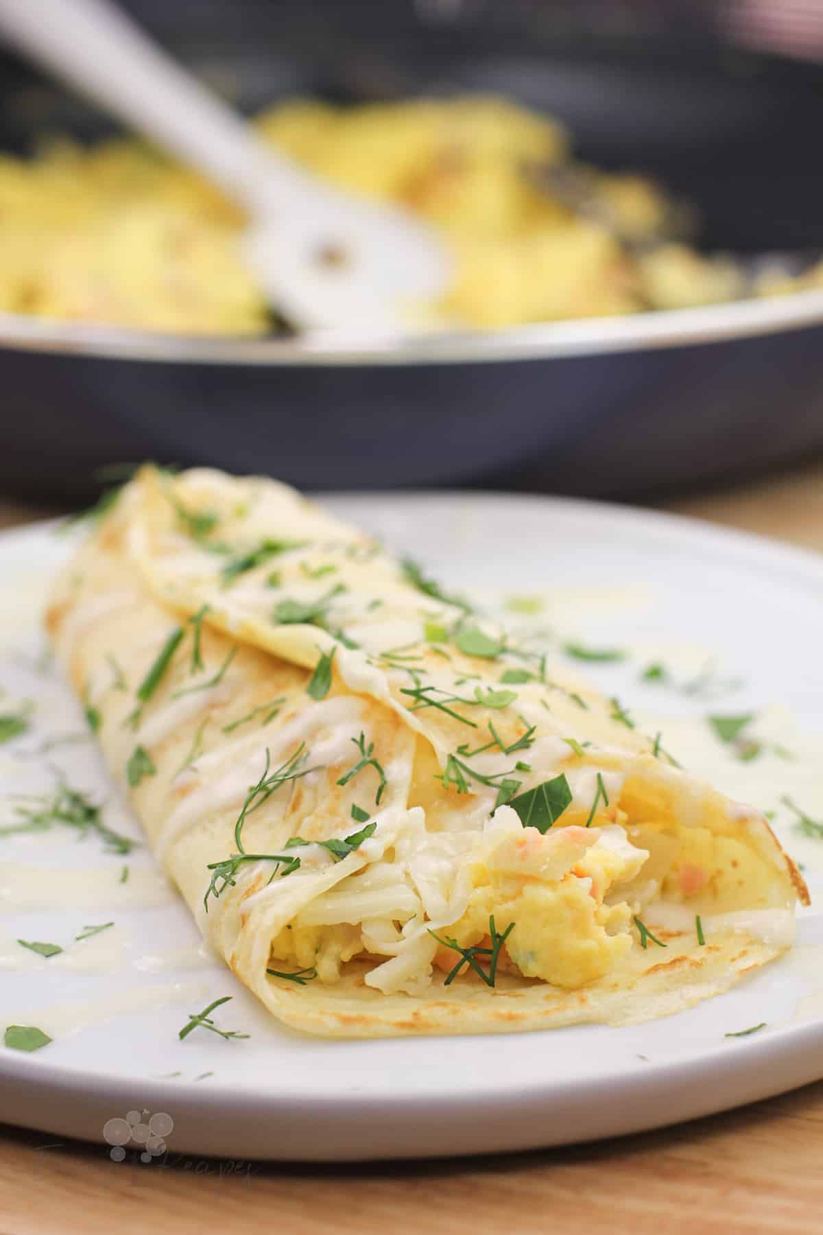 prepared smoked salmon crepe on white dish. skillet in the background