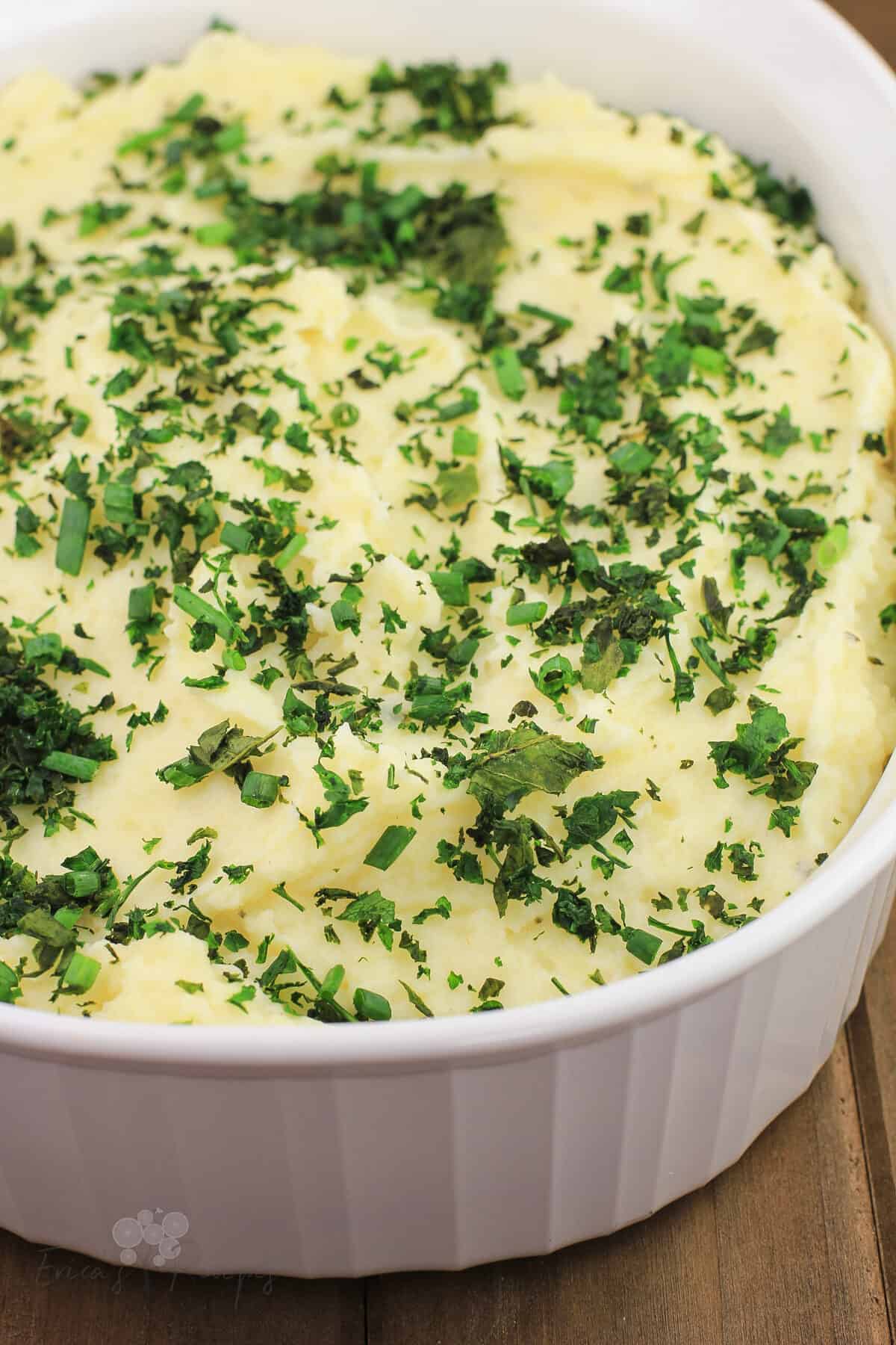 boursin mashed potatoes in white bake dish topped with herbs