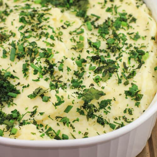 boursin mashed potatoes in white bake dish topped with herbs