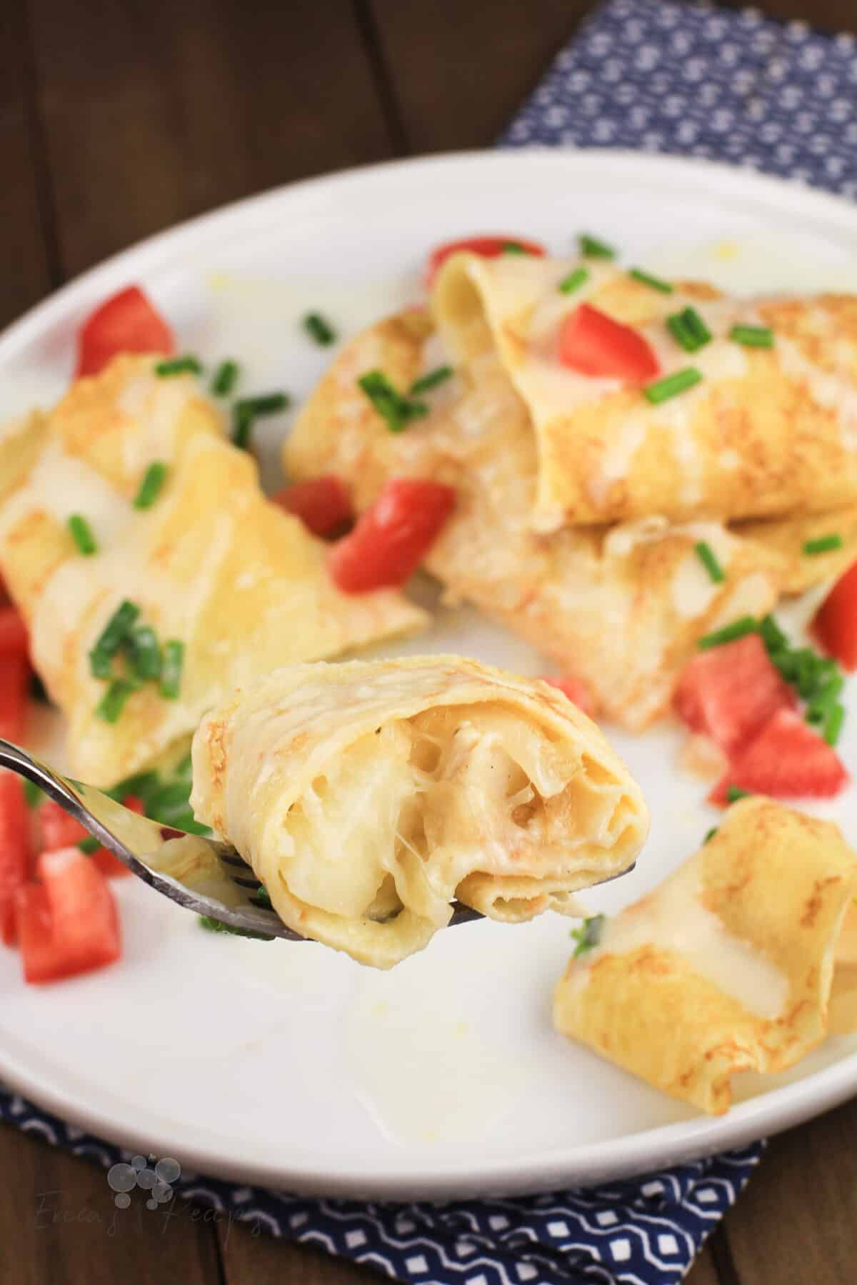 fork holding a bite of crepes with chicken and potato