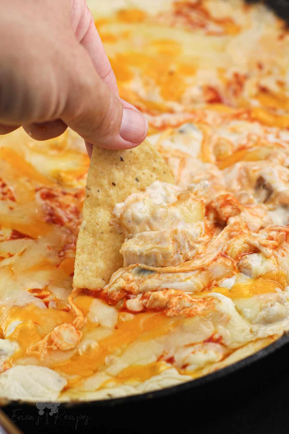 hand holding a chip scooping up smoked buffalo chicken dip