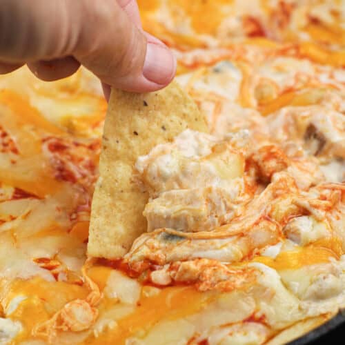 hand holding a chip scooping up smoked buffalo chicken dip