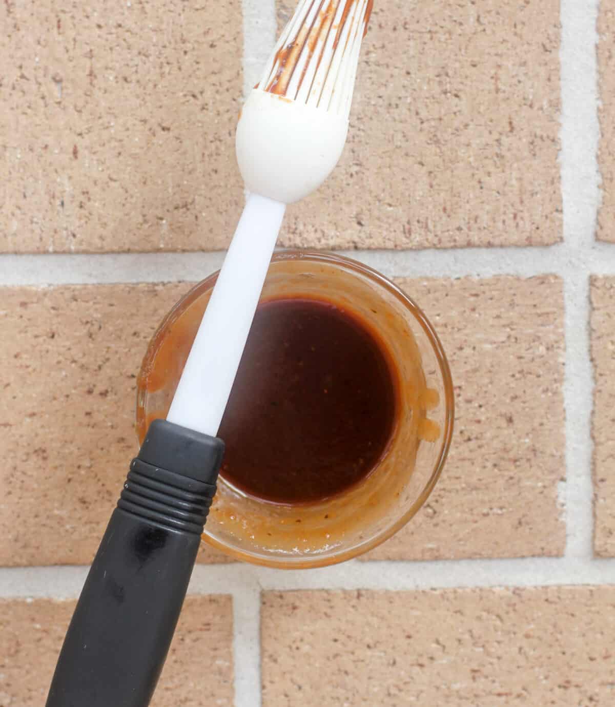 small glass bowl with barbecue sauce; basting brush resting on bowl
