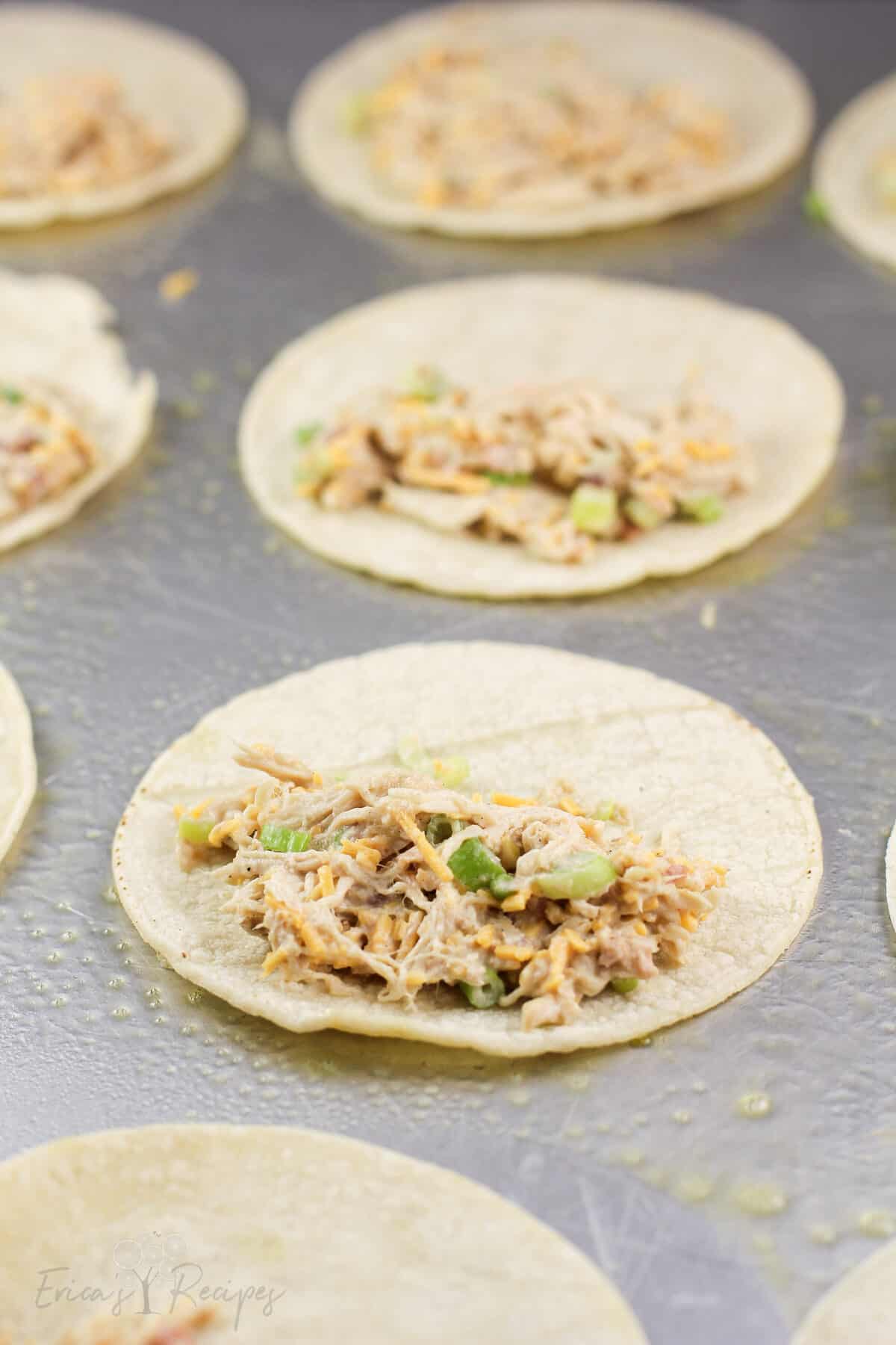 tortilla on bake sheet topped with chicken filling