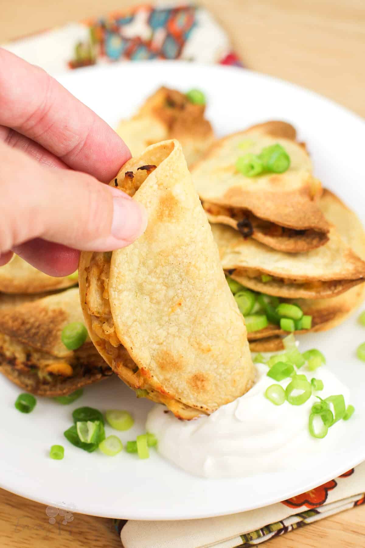 hand dipping quesadilla into sour cream