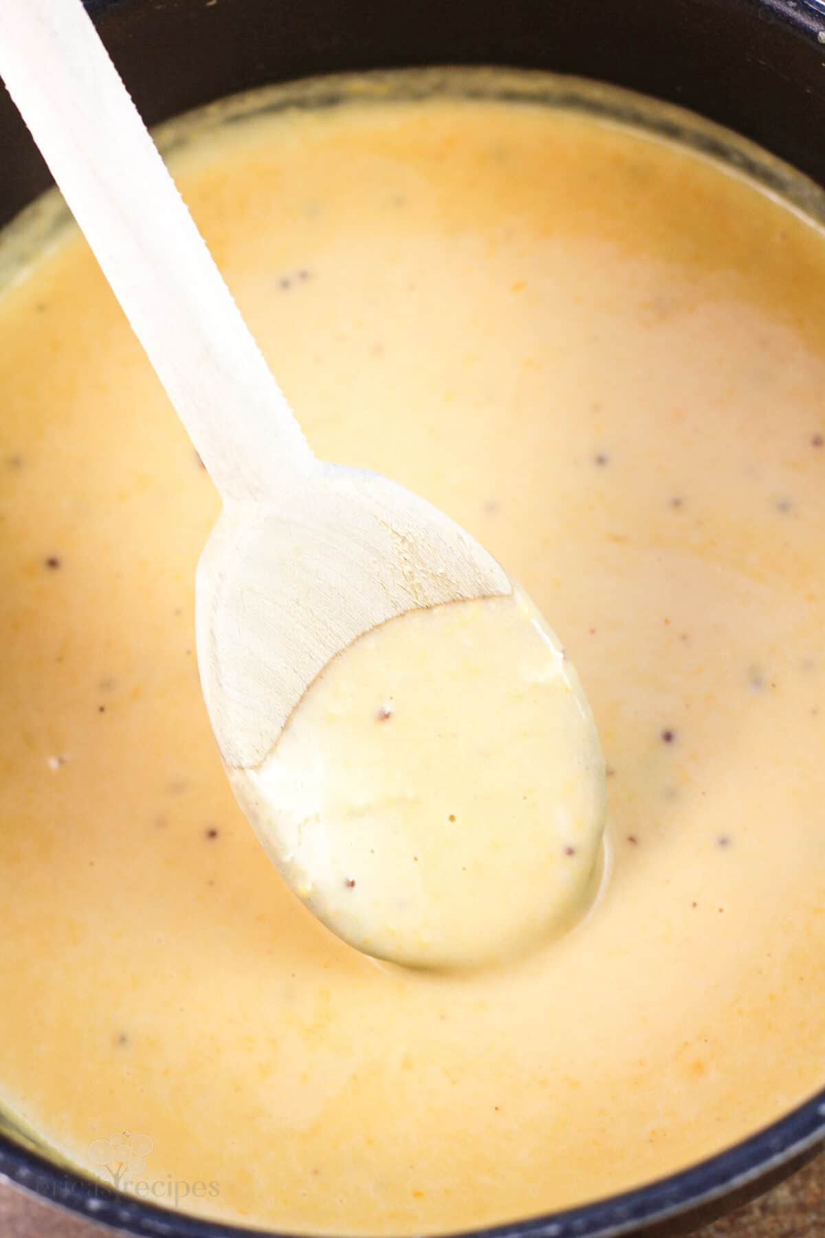 wood spoon in beer cheese in saucepan