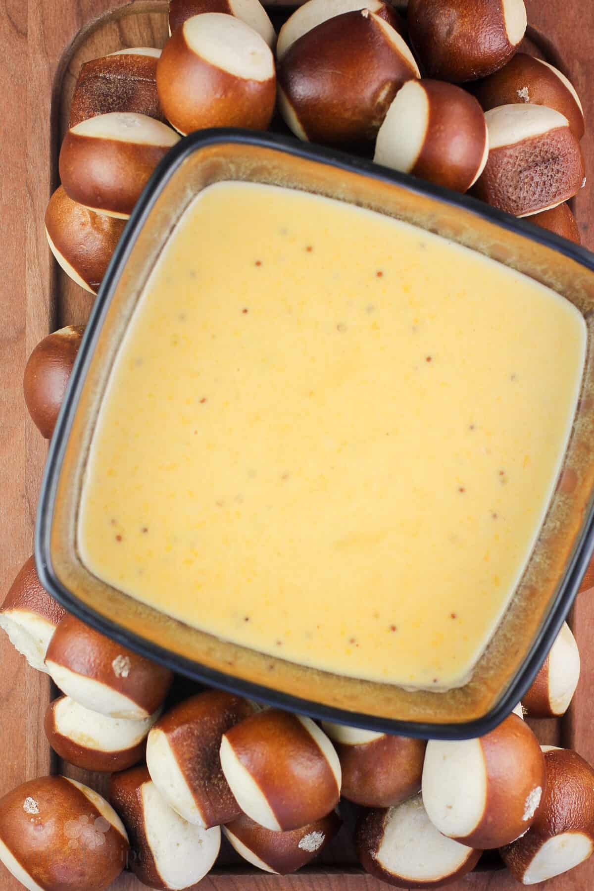 wood platter with bowl of german beer cheese surrounded by pretzel bread bites