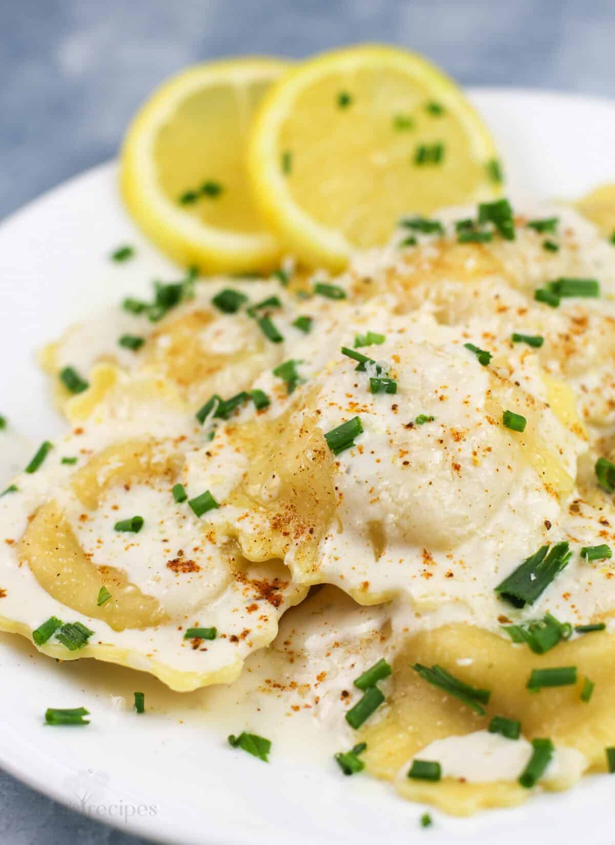 prepared ravioli on white plate with lemon slices on the side