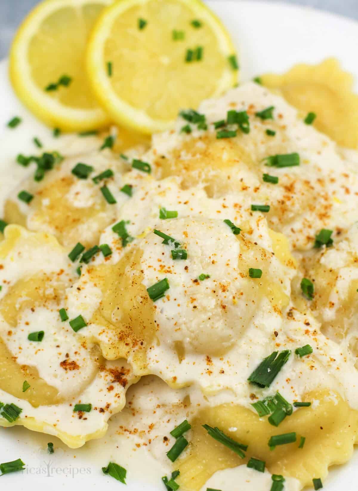 prepared ravioli on white plate with lemon slices on the side