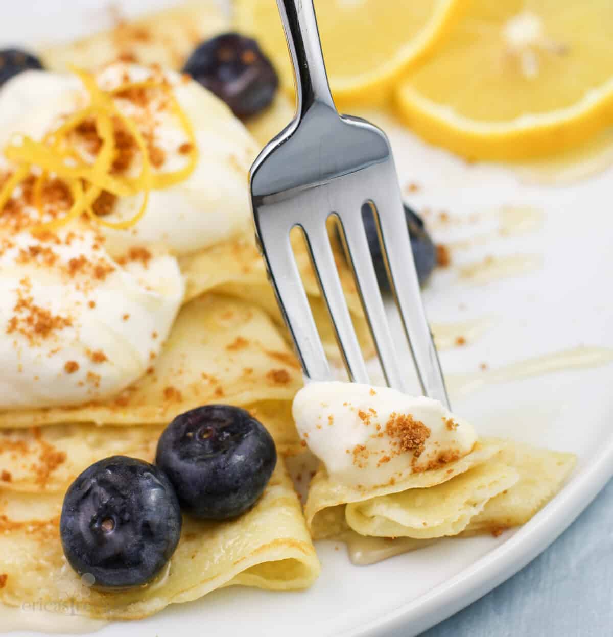 fork with a bite of prepared crepe on white plate