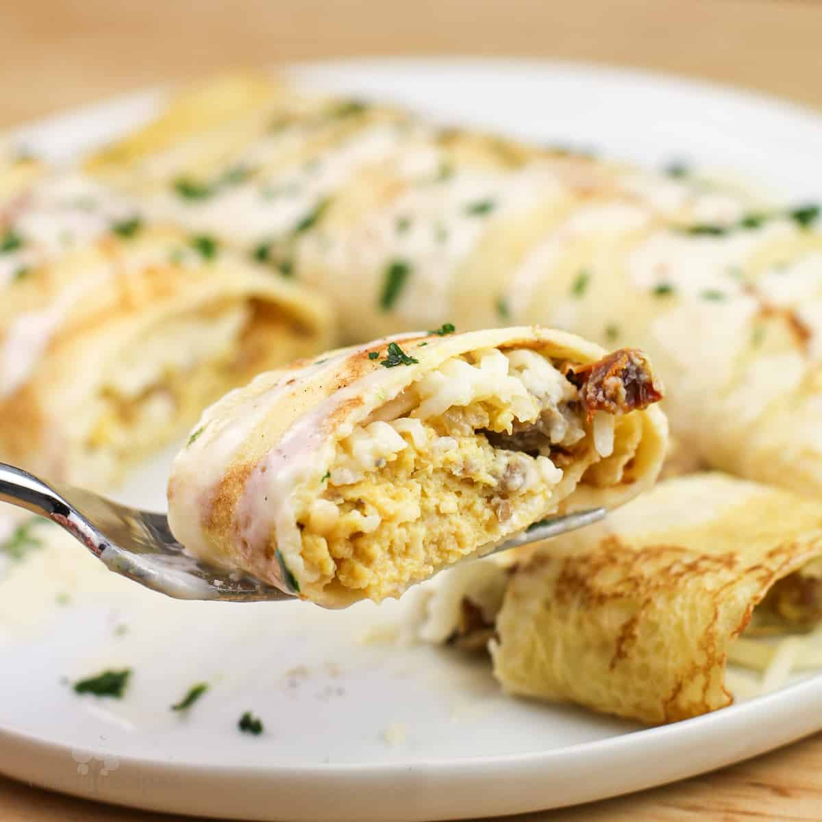 sausage crepe on fork topped with maple bechamel