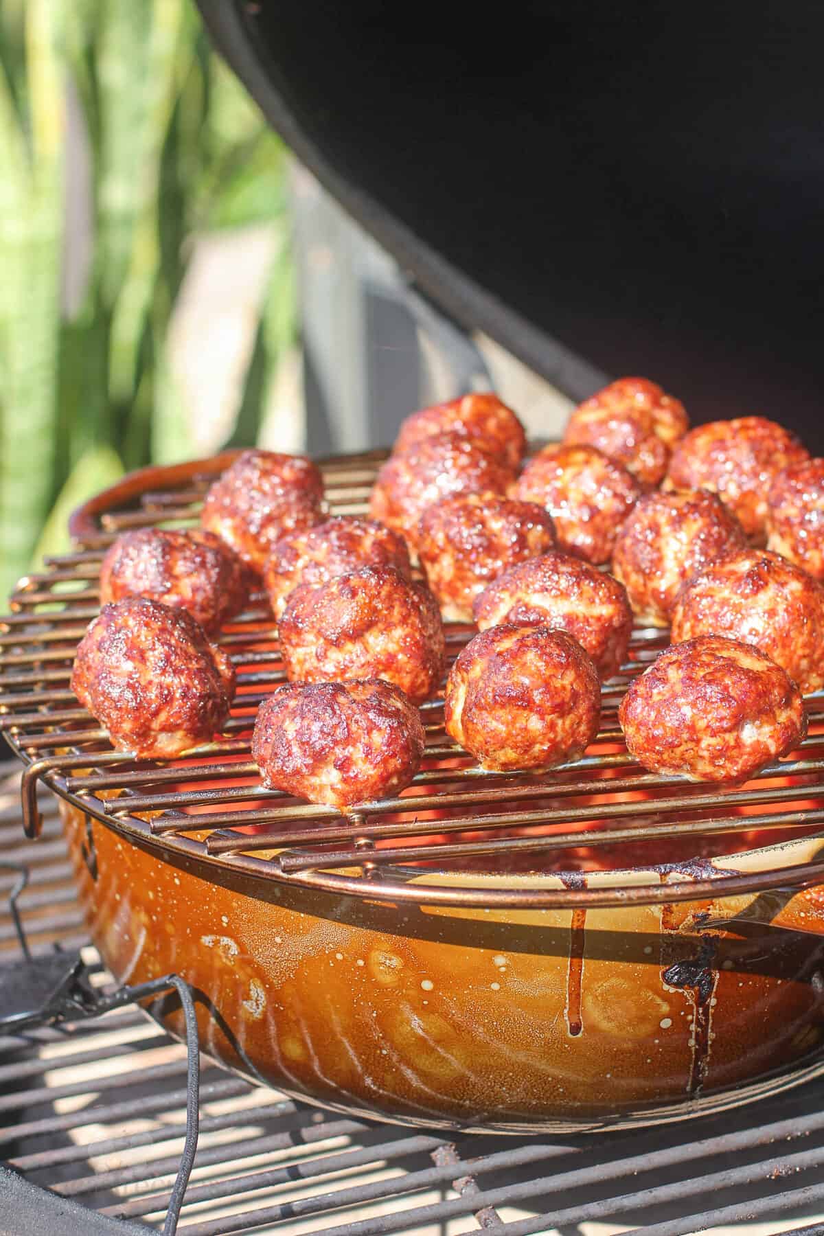 cooked meatballs on rack on dutch oven in big green egg