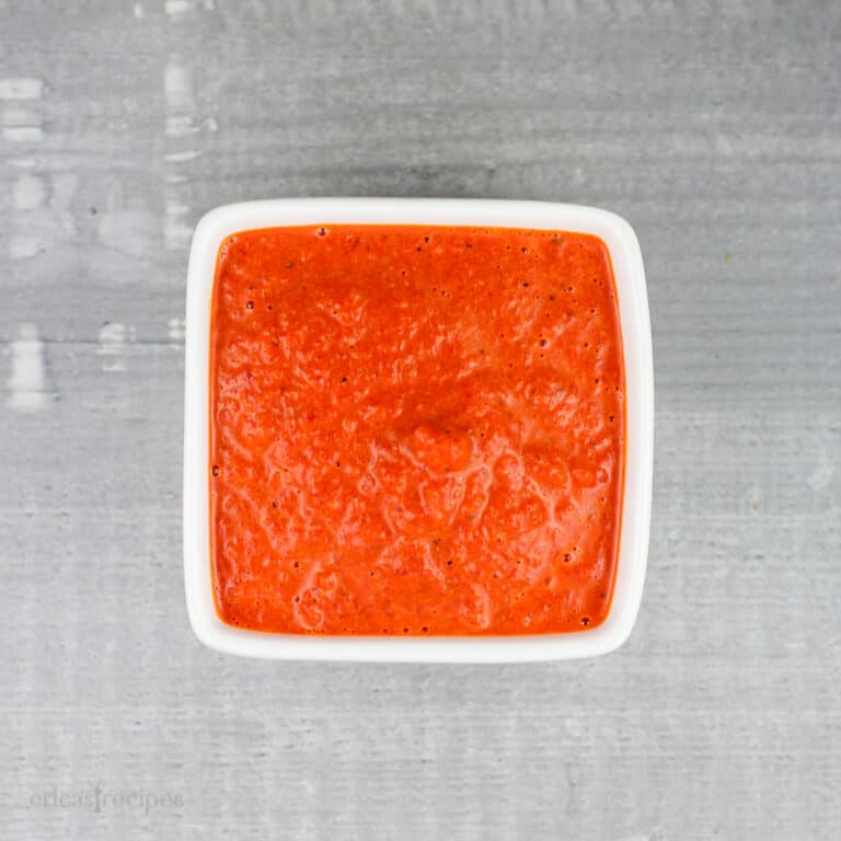 red pepper coulis in small square white bowl on gray rustic surface