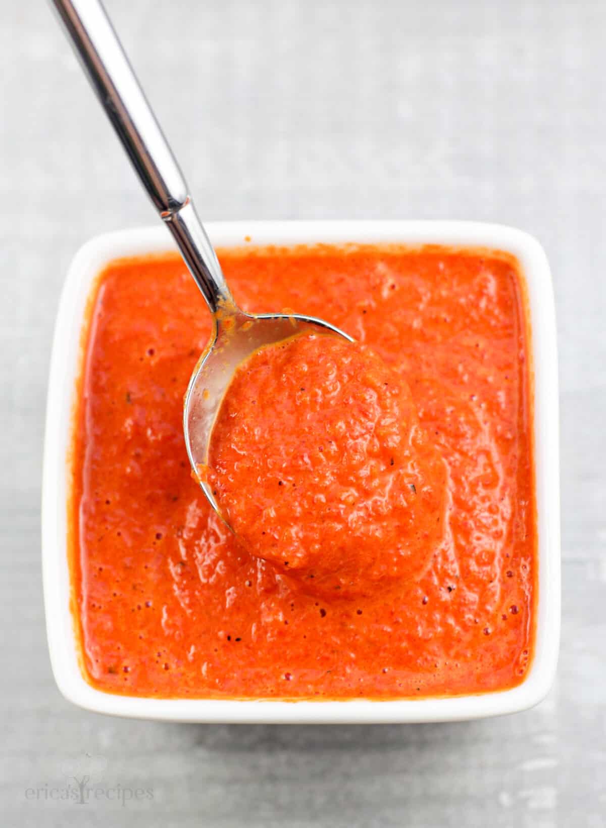 spoon holding coulis in small white bowl