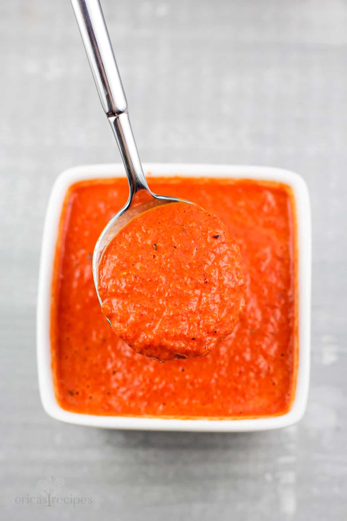 spoon holding coulis in small white bowl