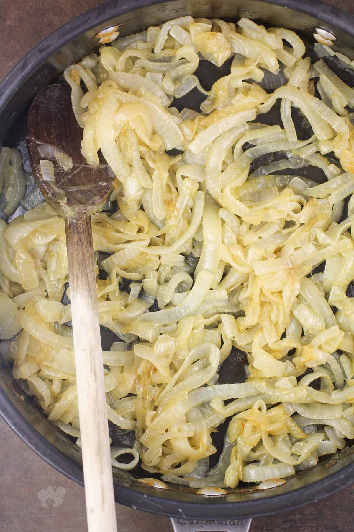 caramelized onions in skillet with wood spoon