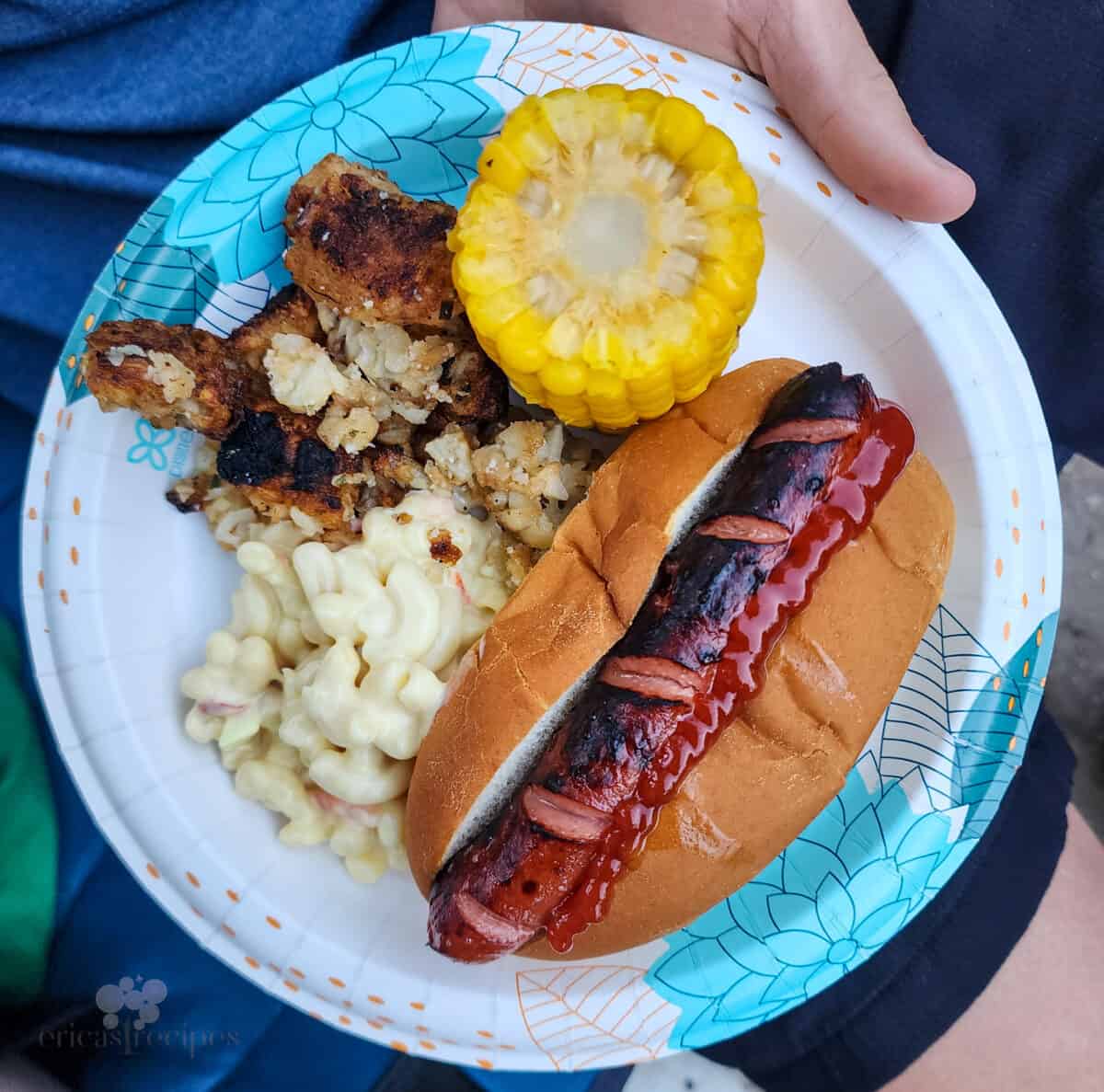 plate of food with hot dog, corn, macaroni salad, and tater tots