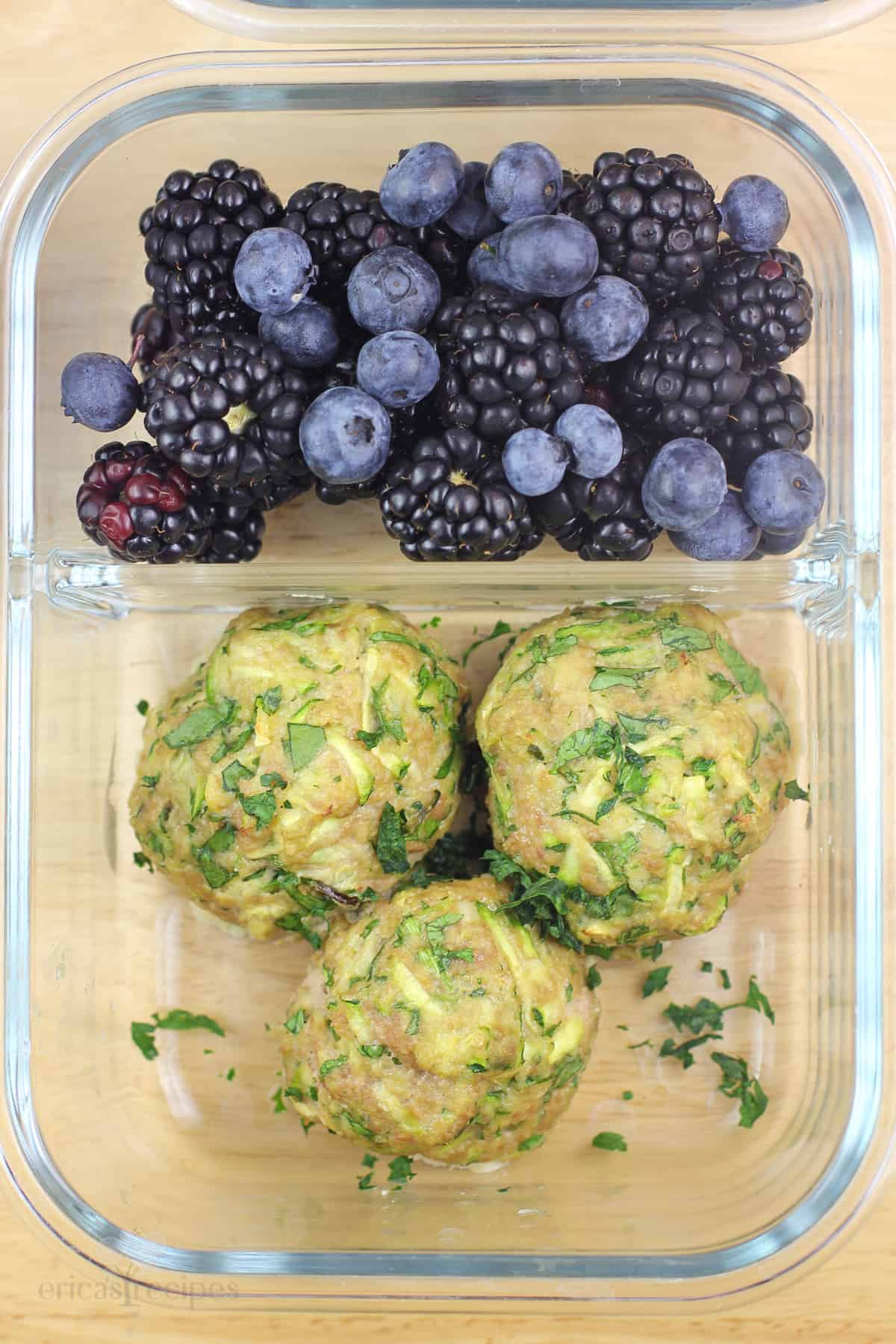 glass meal-prep container with cooked meatballs and fresh berries