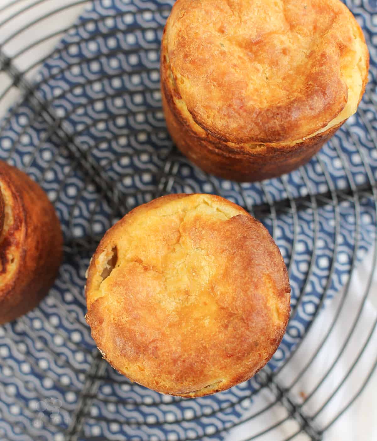 top down view of 3 popovers on wire rack over blue napkin