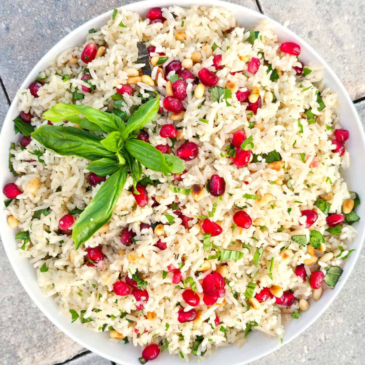 Savory rice salad with pomegranate seeds, fresh herbs, and pine nuts. Perfect for summer parties and healthy side dishes.